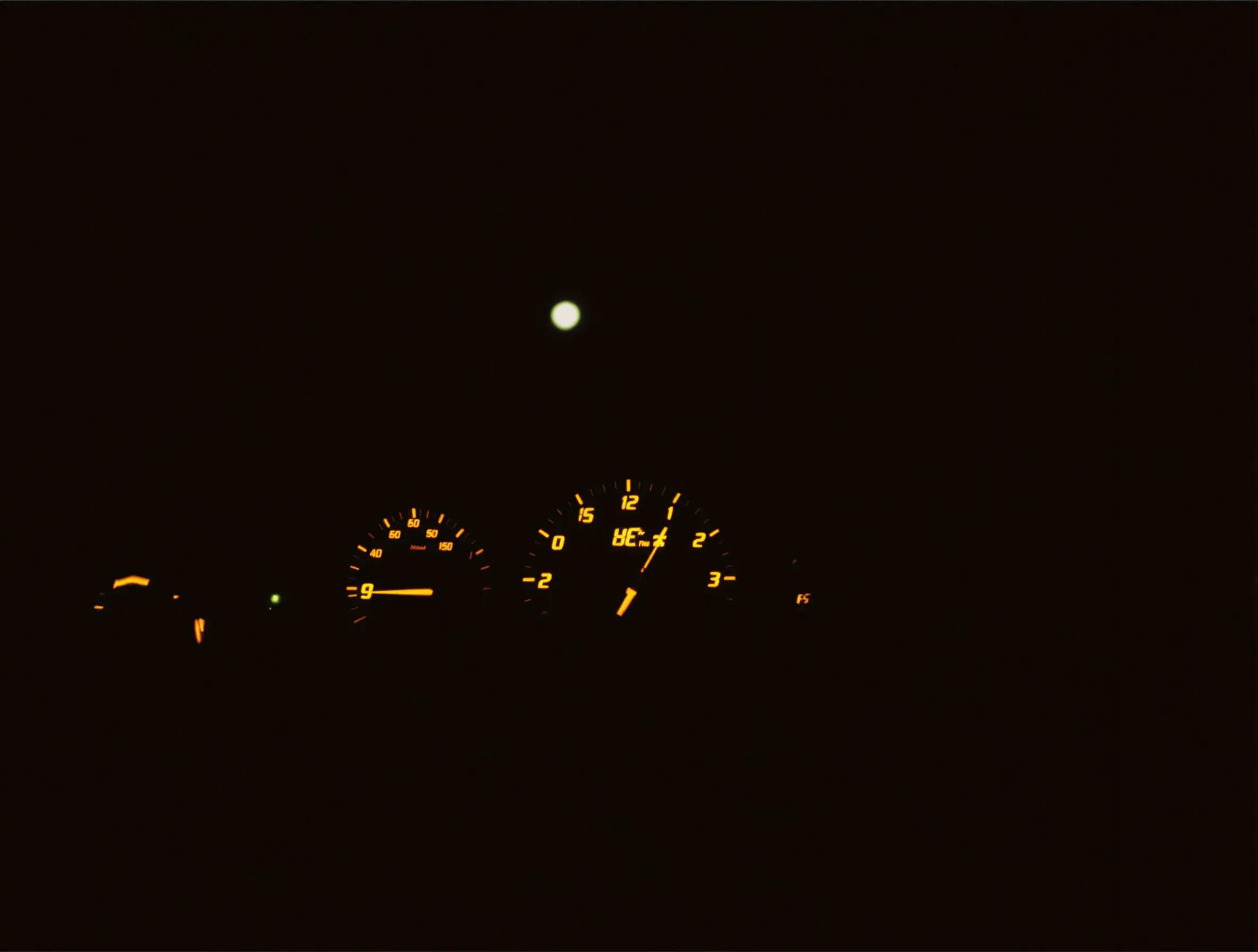 The glowing clock and dials of a car dashboard after midnight
